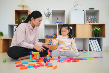 Mutlu bebek kız ve anne evde renkli manyetik inşaat oyuncağı oynuyorlar.