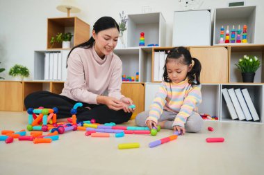 Mutlu bebek kız ve anne evde renkli manyetik inşaat oyuncağı oynuyorlar.