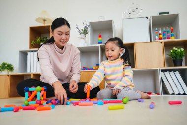 Mutlu bebek kız ve anne evde renkli manyetik inşaat oyuncağı oynuyorlar.
