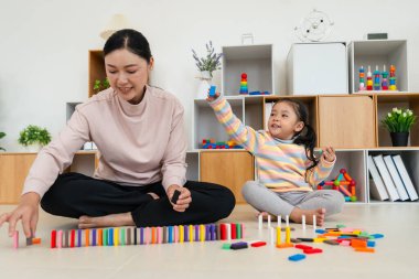 Mutlu küçük kız ve anne renkli tahta blok oyuncağı ya da domino oyunu oynuyorlar.