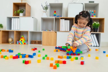 Mutlu küçük kız evde yapı taşı ya da plastik tuğla oyunu oynuyor.