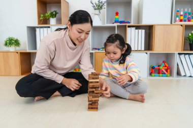 Mutlu küçük kız ve annesi birlikte tahta blok oyuncağı oynuyorlar.