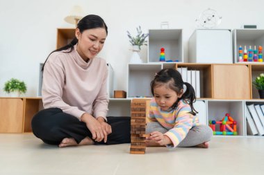 Mutlu küçük kız ve annesi birlikte tahta blok oyuncağı oynuyorlar.