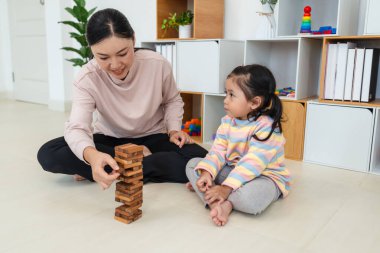 Mutlu küçük kız ve annesi birlikte tahta blok oyuncağı oynuyorlar.