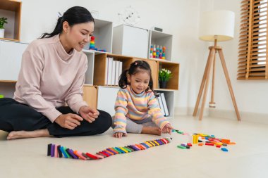 Mutlu küçük kız ve anne renkli tahta blok oyuncağı ya da domino oyunu oynuyorlar.