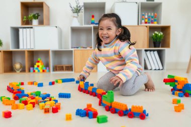 Mutlu küçük kız evde yapı taşı ya da plastik tuğla oyunu oynuyor.