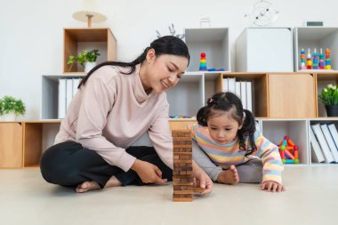 Mutlu küçük kız ve annesi birlikte tahta blok oyuncağı oynuyorlar.