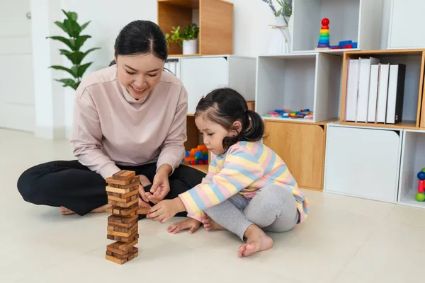 Mutlu küçük kız ve annesi birlikte tahta blok oyuncağı oynuyorlar.
