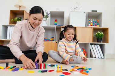 Mutlu küçük kız ve anne renkli tahta blok oyuncağı ya da domino oyunu oynuyorlar.