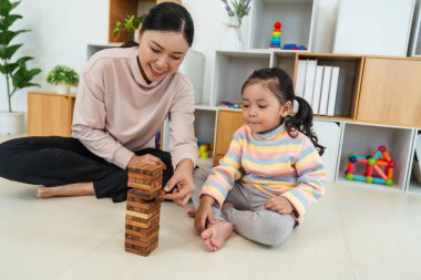 Mutlu küçük kız ve annesi birlikte tahta blok oyuncağı oynuyorlar.