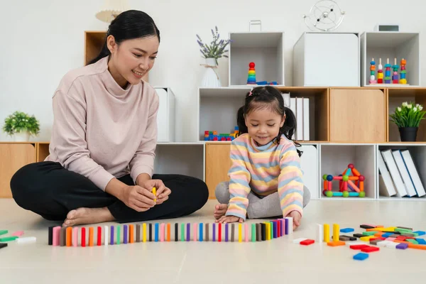 Mutlu küçük kız ve anne renkli tahta blok oyuncağı ya da domino oyunu oynuyorlar.