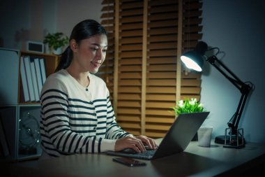 Bir gecede dizüstü bilgisayarla çalışan mutlu kadın.