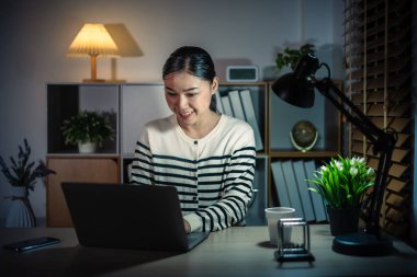 Bir gecede dizüstü bilgisayarla çalışan mutlu kadın.