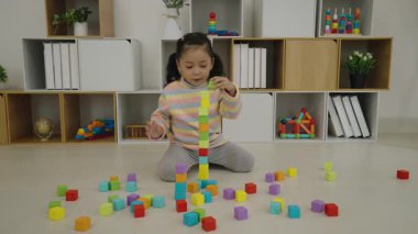 Evde küp inşa eden yığınla blok oyuncağıyla oynayan mutlu kız.