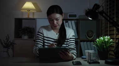 Geceleri dijital tabletle çalışan mutlu kadın.