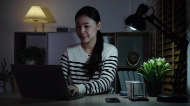 Bir gecede dizüstü bilgisayarla çalışan mutlu kadın.