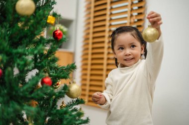 Oyuncak top tutan mutlu küçük kız. Evdeki Noel ağacını süslemek.
