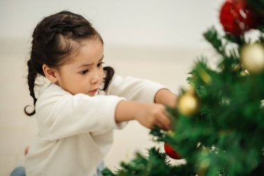 Mutlu küçük kız evde Noel ağacını süslüyor.