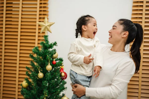 Mutlu anne ve küçük kız evde Noel ağacı süslüyorlar.