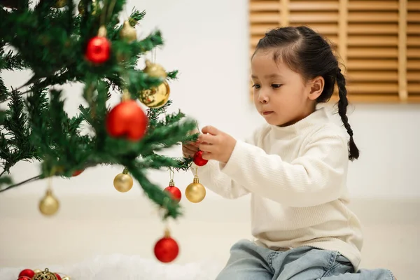 Mutlu küçük kız evde Noel ağacında oyuncak balosu düzenliyor.