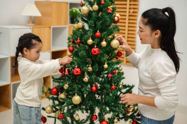 Mutlu anne ve küçük kız evde Noel ağacı süslüyorlar.