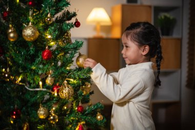 Mutlu küçük kız evde Noel ağacında oyuncak balosu düzenliyor.