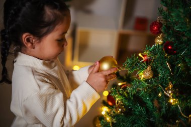 Mutlu küçük kız evde Noel ağacında oyuncak balosu düzenliyor.