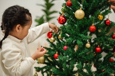 Mutlu küçük kız evde Noel ağacında oyuncak balosu düzenliyor.