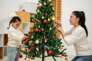 Mutlu anne ve küçük kız evde Noel ağacı süslüyorlar.