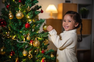 Mutlu küçük kız evde Noel ağacında oyuncak balosu düzenliyor.