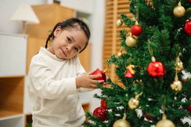Mutlu küçük kız evde Noel ağacında oyuncak balosu düzenliyor.