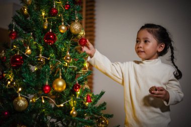 Mutlu küçük kız evde Noel ağacında oyuncak balosu düzenliyor.