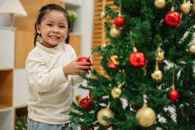 Mutlu küçük kız evde Noel ağacında oyuncak balosu düzenliyor.