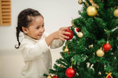 Mutlu küçük kız evde Noel ağacında oyuncak balosu düzenliyor.