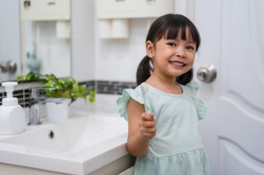 Kız çocuk banyoda dişlerini fırçalıyor.