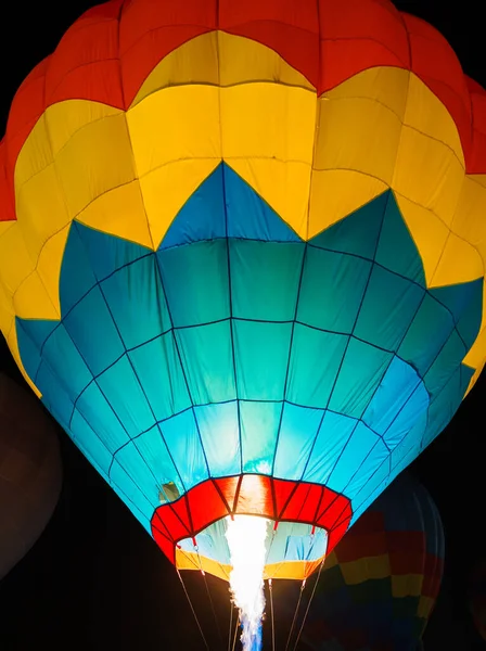 Karanlık gece gökyüzünde parlayan renkli sıcak hava balonları