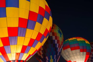 Karanlık gece gökyüzünde parlayan renkli sıcak hava balonları