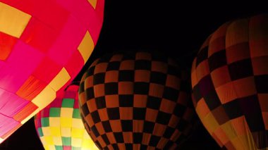 Karanlık gece gökyüzünde parlayan renkli sıcak hava balonları