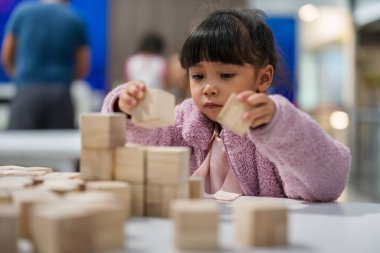 Anaokulundaki kız çocuğu ahşap bloklu bir kule inşa etmeye odaklanmış.