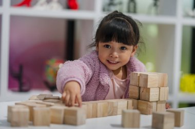 Anaokulundaki kız çocuğu ahşap bloklu bir kule inşa etmeye odaklanmış.