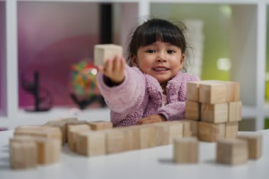 Anaokulundaki kız çocuğu ahşap bloklu bir kule inşa etmeye odaklanmış.