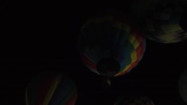 Karanlık gece gökyüzünde parlayan renkli sıcak hava balonları