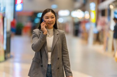 Alışveriş merkezinde alışveriş yaparken konuşan bir kadın.