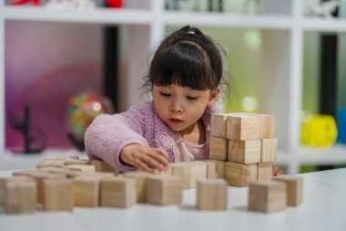 Anaokulundaki kız çocuğu ahşap bloklu bir kule inşa etmeye odaklanmış.