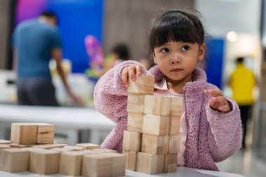 Anaokulundaki kız çocuğu ahşap bloklu bir kule inşa etmeye odaklanmış.