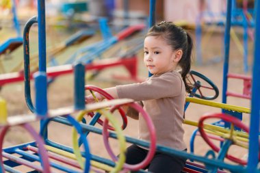 Çocuk kız oyun parkında direksiyon oyuncağıyla oynuyor.