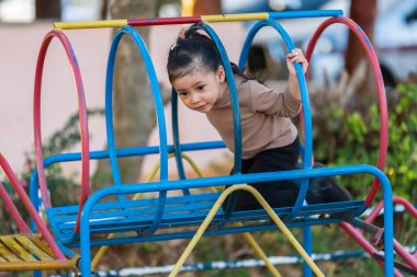 Çocuk, halka açık bir oyun parkındaki renkli metal tünel yapısında sürünüyor.