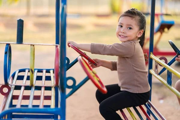 Çocuk kız oyun parkında direksiyon oyuncağıyla oynuyor.