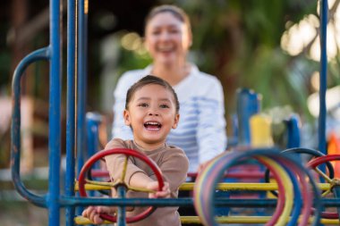 Çocuk kız annesiyle oyun parkında direksiyon oyuncağıyla oynuyor.