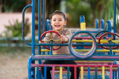 Çocuk kız oyun parkında direksiyon oyuncağıyla oynuyor.